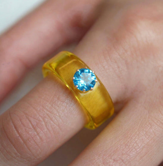 Anillo CG de topacio Swiss Blue y resina amarilla, puesto en la mano