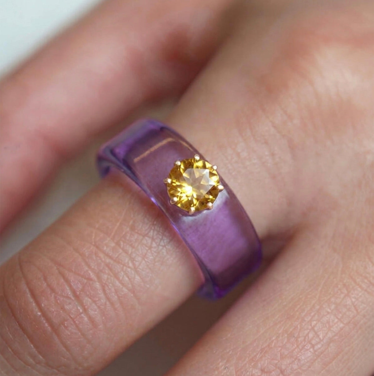 Anillo CG de citrino y resina morada, puesto en la mano