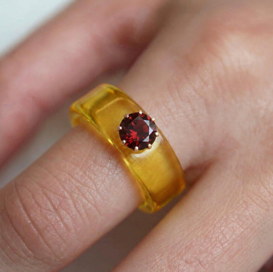 Anillo CG de granate y resina amarilla, puesto en la mano