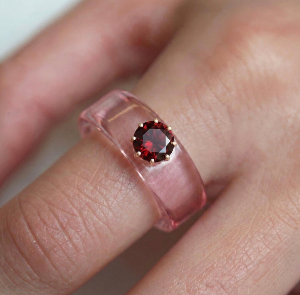 Anillo CG de granate y resina rosa, puesto en la mano