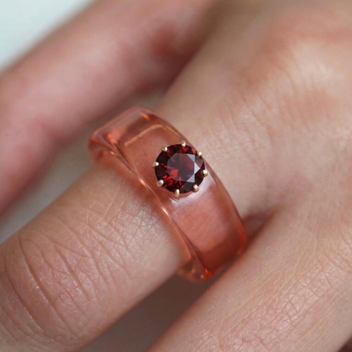 Anillo CG de granate y resina salmón, puesto en la mano