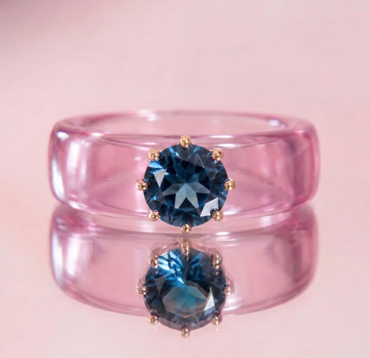 Anillo CG de topacio London Blue y resina rosa, puesto en la mano