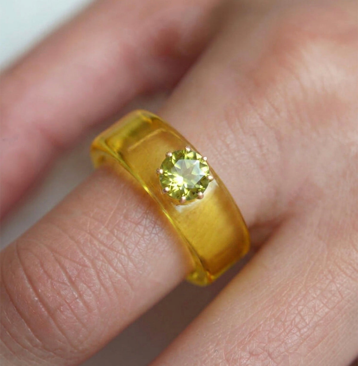 Anillo CG de peridoto y resina amarilla, puesto en la mano