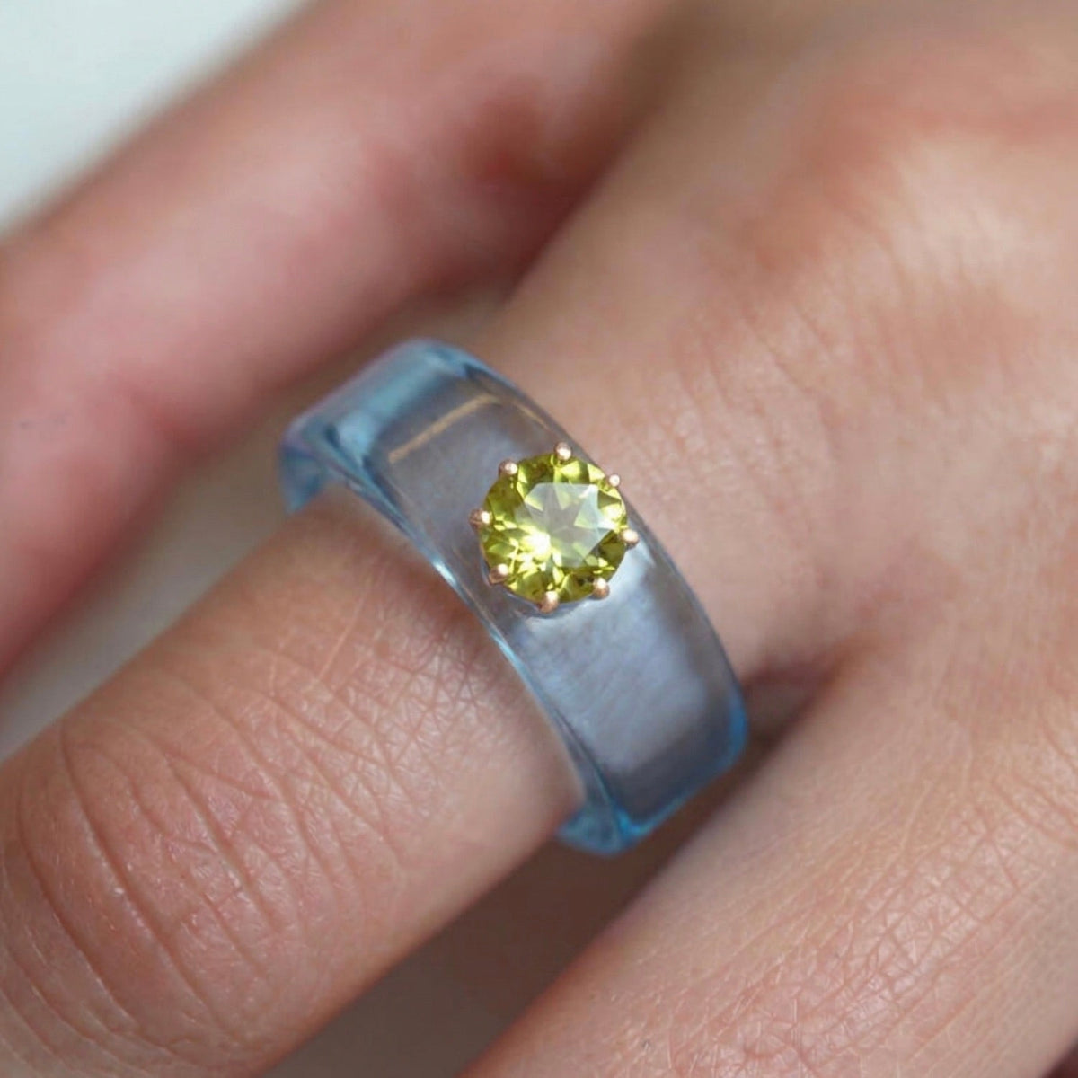Anillo CG de peridoto y resina celeste, puesto en la mano