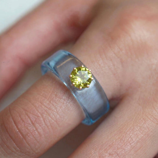 Anillo CG de peridoto y resina celeste, puesto en la mano