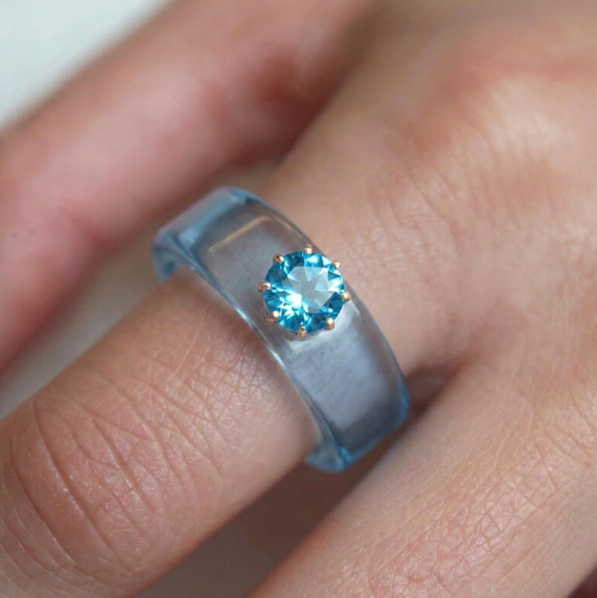 Anillo CG de topacio Swiss Blue y resina celeste, puesto en la mano