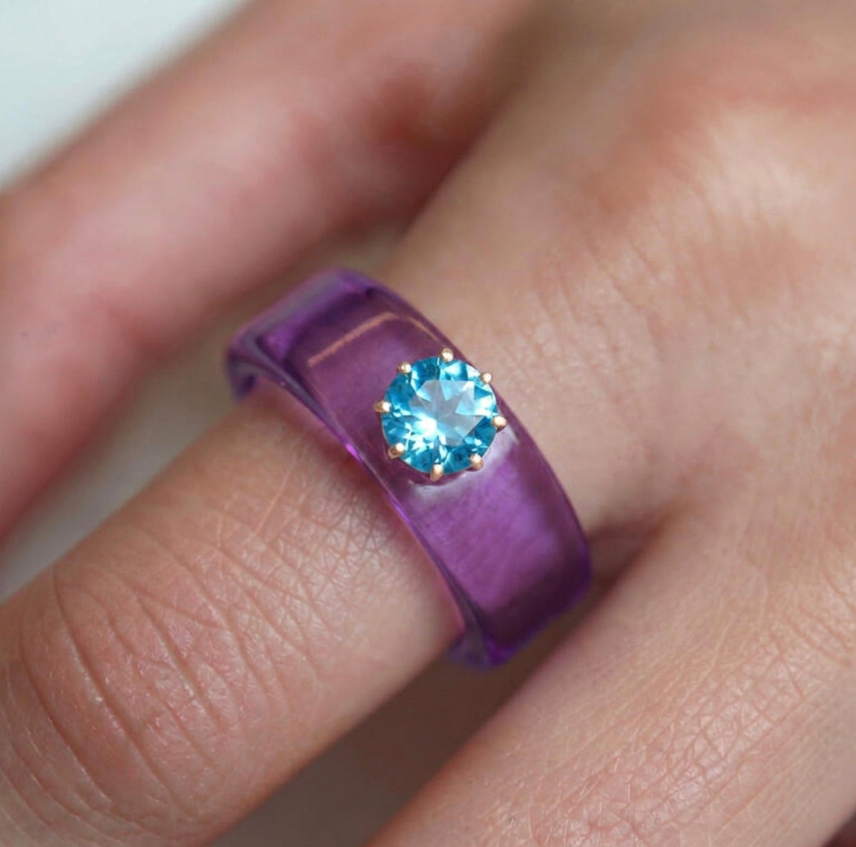 Anillo CG de topacio Swiss Blue y resina morada, puesto en la mano