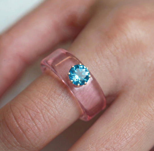 Anillo CG de topacio Swiss Blue y resina rosa, puesto en la mano