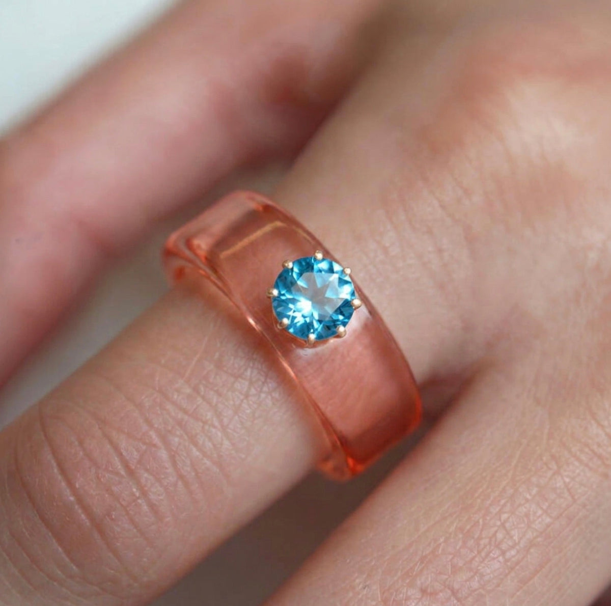 Anillo CG de topacio Swiss Blue y resina salmón, puesto en la mano
