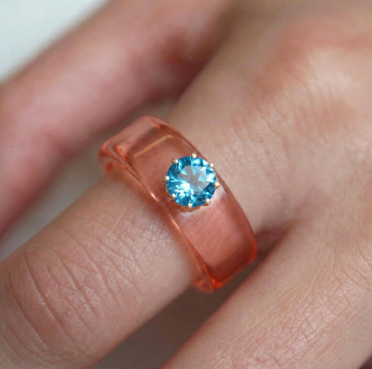 Anillo CG de topacio Swiss Blue y resina salmón, puesto en la mano